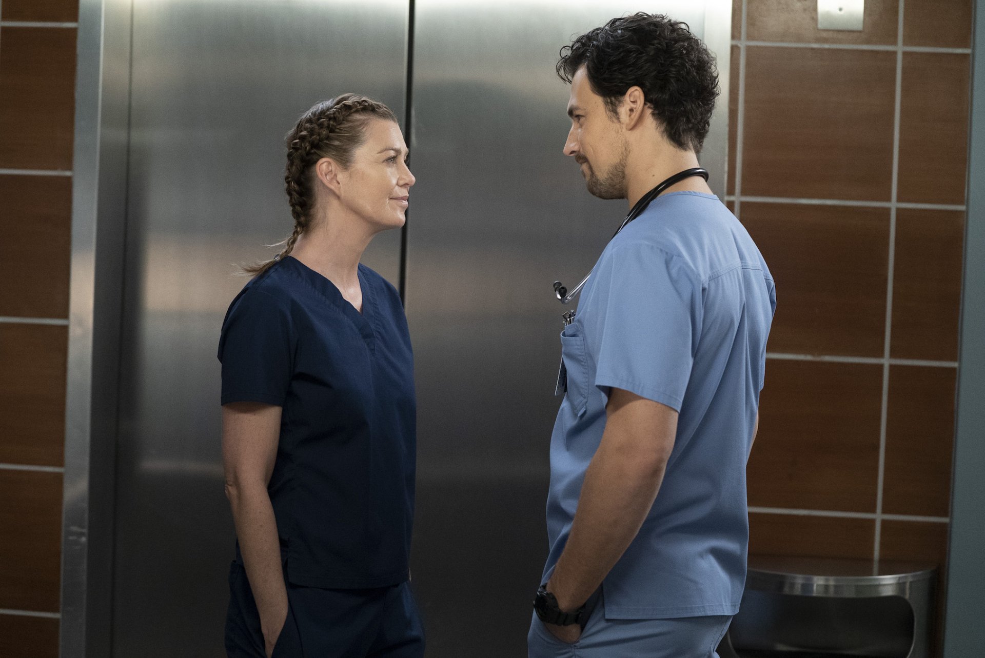 HD desktop wallpaper of two characters from Grey's Anatomy in medical scrubs having a conversation.