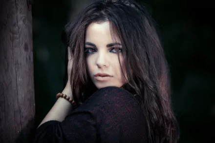 HD PC desktop wallpaper featuring a brunette woman with brown eyes and a captivating expression against a dark, blurred background.