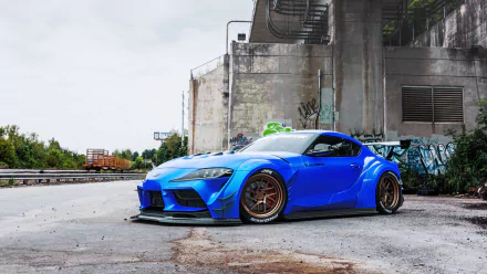 Blue Toyota Supra A90 sports car parked in an urban industrial lot — HD PC desktop wallpaper and background.