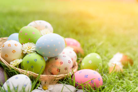 Colorful Easter eggs with floral patterns rest in grass, bathed in warm sunlight, creating a vibrant holiday scene for a 4K Ultra HD PC desktop wallpaper.