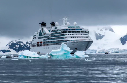 HD desktop wallpaper showing the MV Seabourn Quest cruise ship navigating icy Antarctic waters surrounded by icebergs and snow-covered mountains.