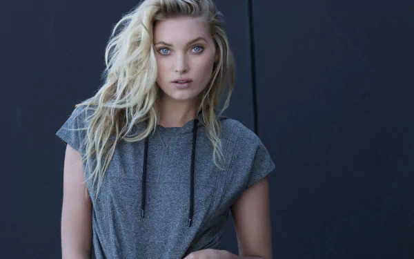 2K Quad HD desktop wallpaper of a blonde Swedish model — woman in a grey tee with tousled hair and blue eyes, posed against a dark, minimalist backdrop.