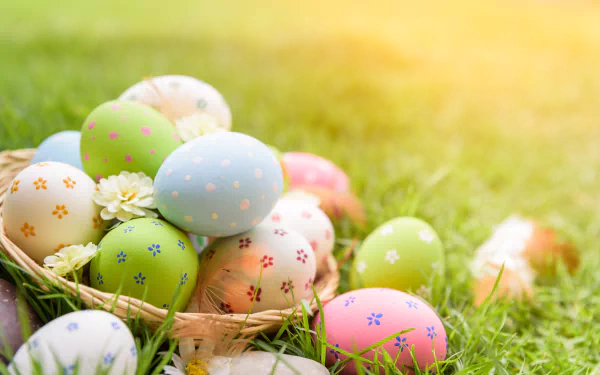Colorful Easter eggs with floral patterns rest in grass, bathed in warm sunlight, creating a vibrant holiday scene for a 4K Ultra HD PC desktop wallpaper.