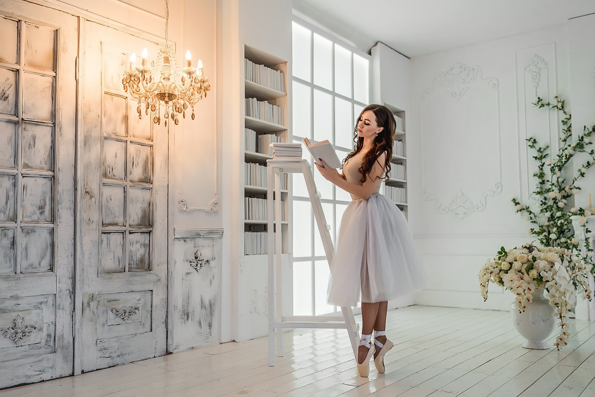 HD desktop wallpaper of a brunette ballerina model woman reading a book on pointe in a bright, elegant white studio, soft mood lighting.