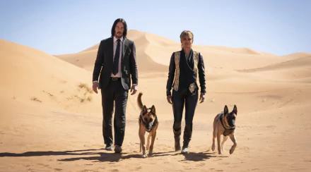 Two lead characters and two German shepherds stride across sunlit desert dunes in a scene from John Wick: Chapter 3 – Parabellum, 2K Quad HD PC desktop wallpaper.
