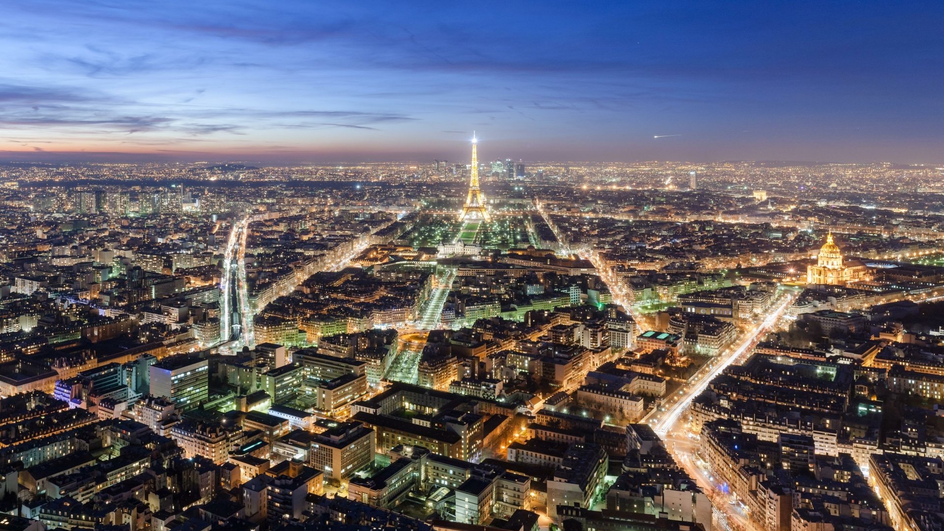 Nighttime aerial view of Paris, France, featuring the illuminated Eiffel Tower and glowing city lights in vibrant 4K Ultra HD detail.