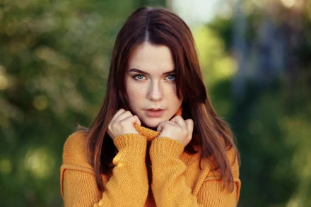 Redhead woman model with blue eyes and freckles gazes forward in a mustard sweater; shallow depth of field bokeh, HD PC desktop wallpaper/background.