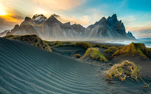Vibrant 4K Ultra HD wallpaper showcasing Iceland’s Vestrahorn mountains with black sand dunes and mossy patches under a colorful sky.