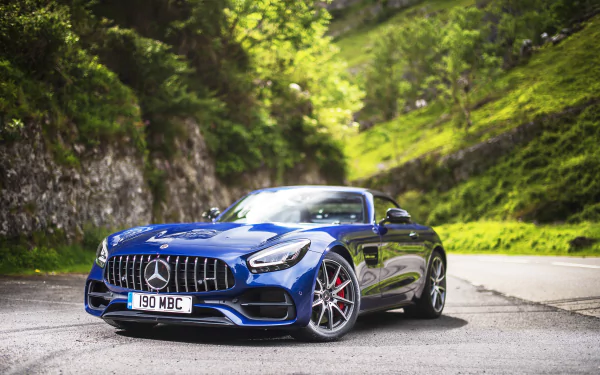 Blue Mercedes‑Benz AMG GT vehicle on a mountain road, 5K Ultra HD PC desktop wallpaper background showcasing the AMG sports car's grille, wheels and sleek profile.