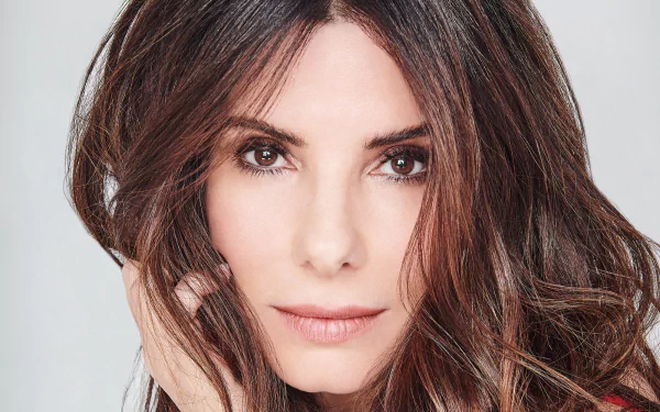 Close-up HD desktop wallpaper of American actress Sandra Bullock with brunette hair and brown eyes, staring directly at the camera.