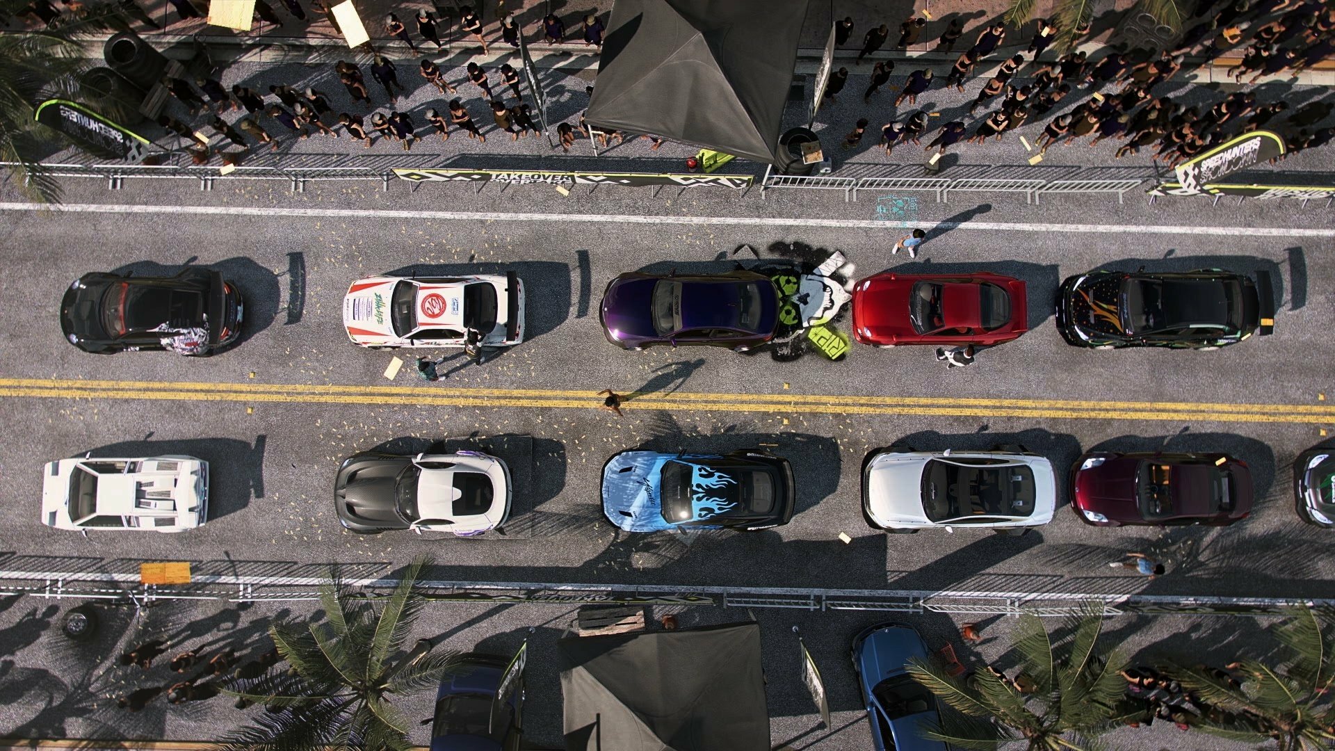 Top-down HD PC desktop wallpaper/background from the video game Need for Speed Heat showing colorful sports cars lined on a sunlit city street with palm trees and crowds.