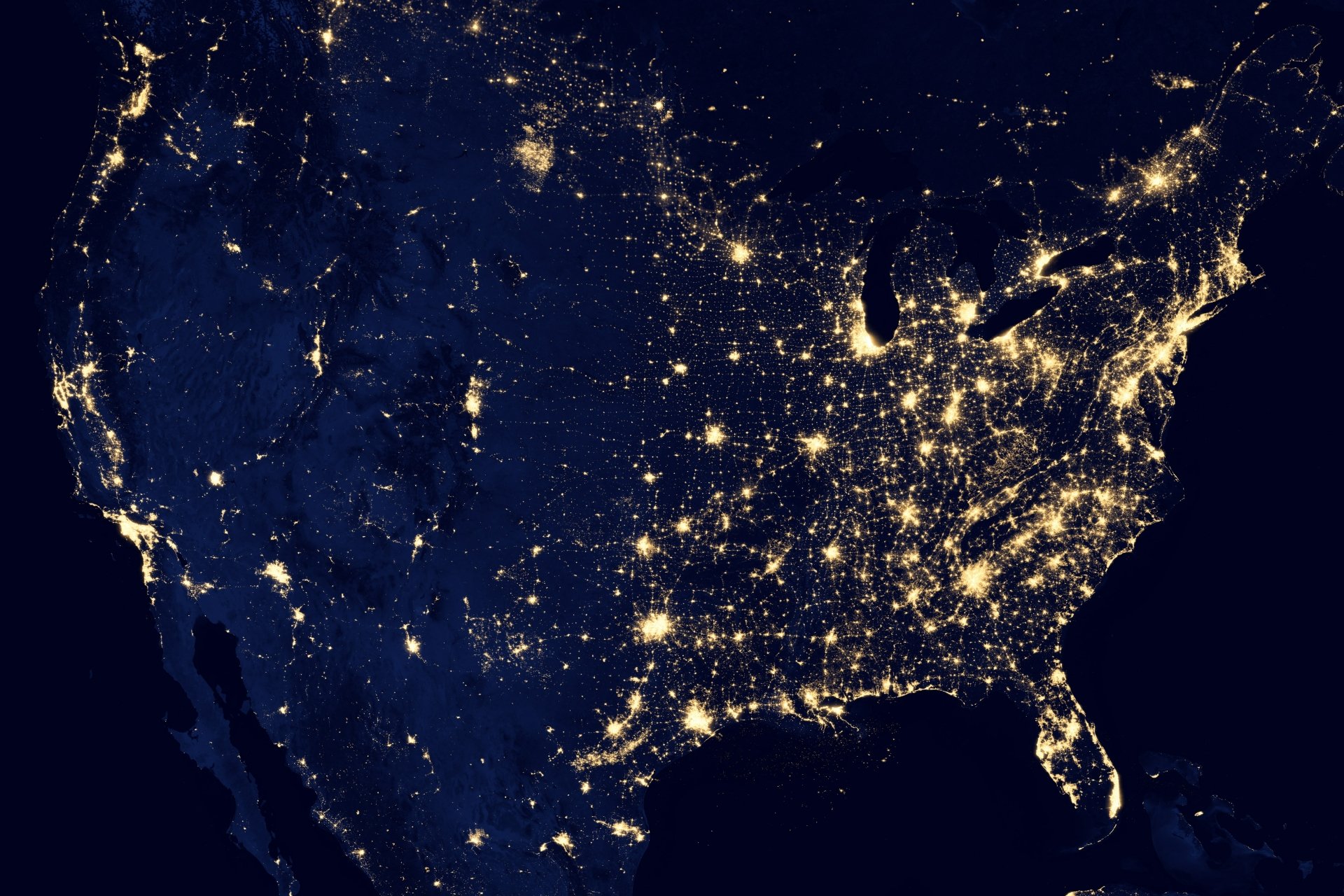 4K Ultra HD image of the United States at night from space, showing illuminated cities and natural landforms across the continent.