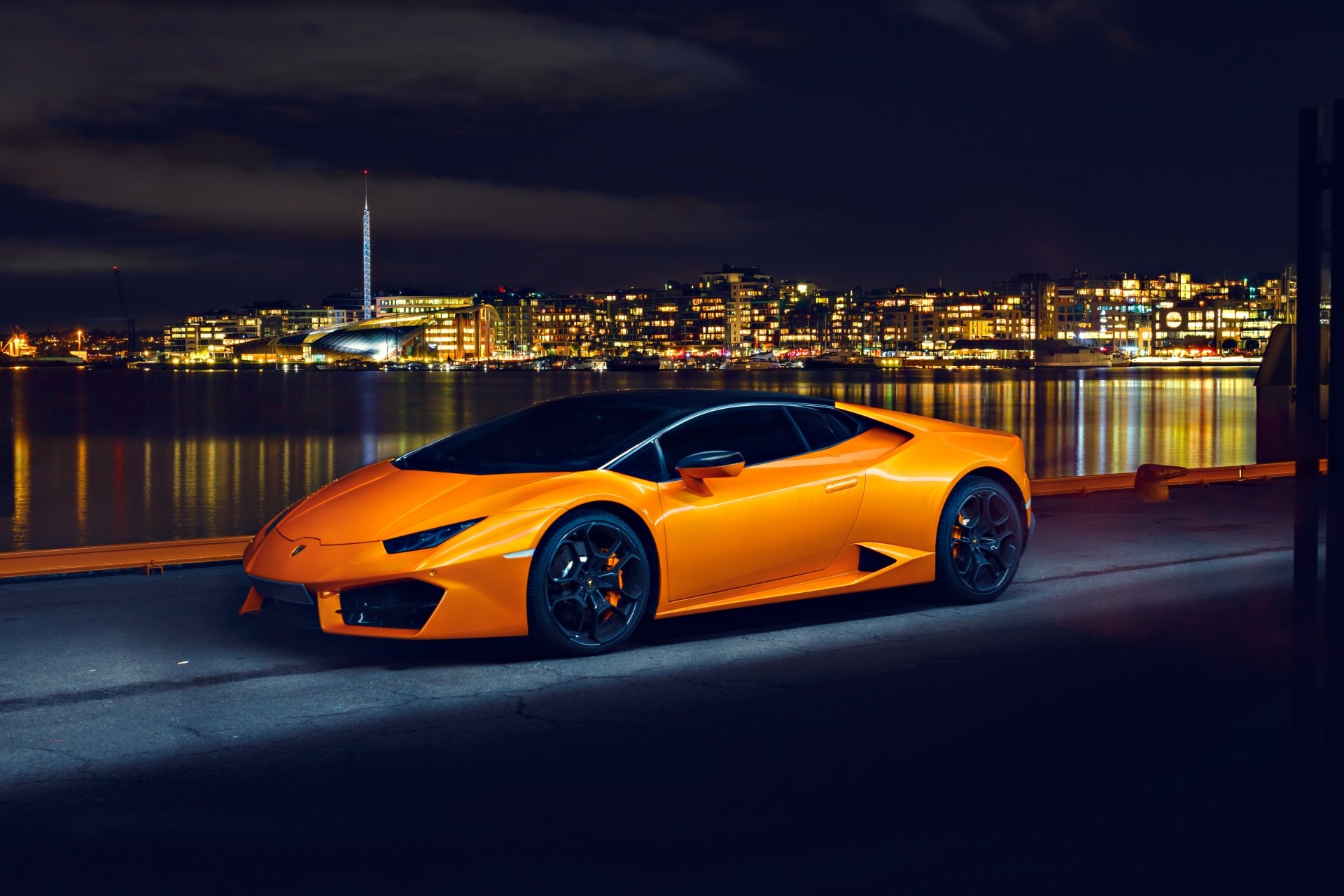 Orange Lamborghini Huracan supercar parked by a waterfront at night, captured in stunning 4K Ultra HD for a vibrant PC desktop wallpaper background.