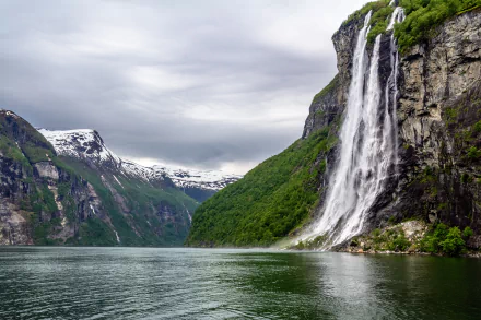 A stunning 4K Ultra HD desktop wallpaper showcasing a dramatic waterfall cascading down a Norwegian fjord mountain, surrounded by lush greenery and calm waters.