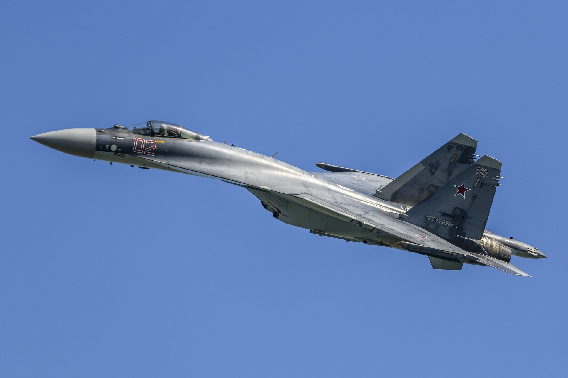 HD desktop wallpaper showing a Sukhoi Su-35 military jet fighter soaring against a clear blue sky.