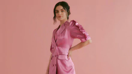 HD desktop wallpaper of an American actress and celebrity with black hair in a pink satin dress against a soft peach backdrop.