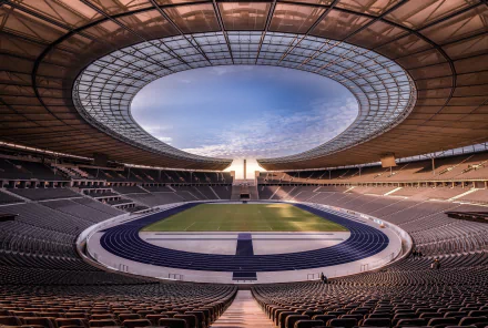 Interior view of Berlin Olympic Stadium, Germany — sweeping oval roof, blue athletics track and central pitch, rendered as a 4K Ultra HD PC desktop wallpaper background.