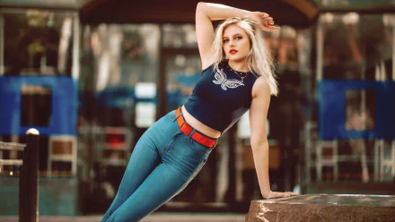 A blonde woman with blue eyes and lipstick poses in denim jeans and a sleeveless top, captured with a shallow depth of field in a 4K Ultra HD wallpaper image.