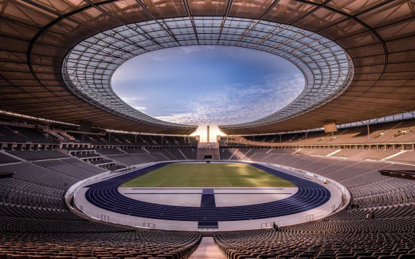Interior view of Berlin Olympic Stadium, Germany — sweeping oval roof, blue athletics track and central pitch, rendered as a 4K Ultra HD PC desktop wallpaper background.