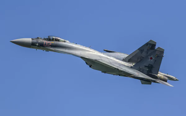 HD desktop wallpaper showing a Sukhoi Su-35 military jet fighter soaring against a clear blue sky.