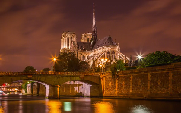 Night view of Notre-Dame de Paris on the Seine, the cathedral warmly illuminated with shimmering river reflections — HD PC desktop wallpaper background.