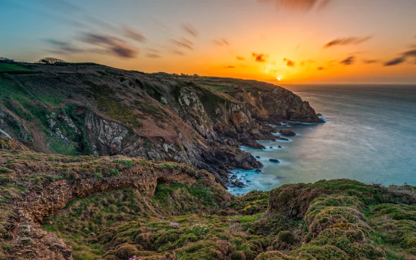 2K Quad HD desktop wallpaper: Brittany sunset over rugged French coastline, cliffs plunging to the ocean with golden sky and tranquil waves.