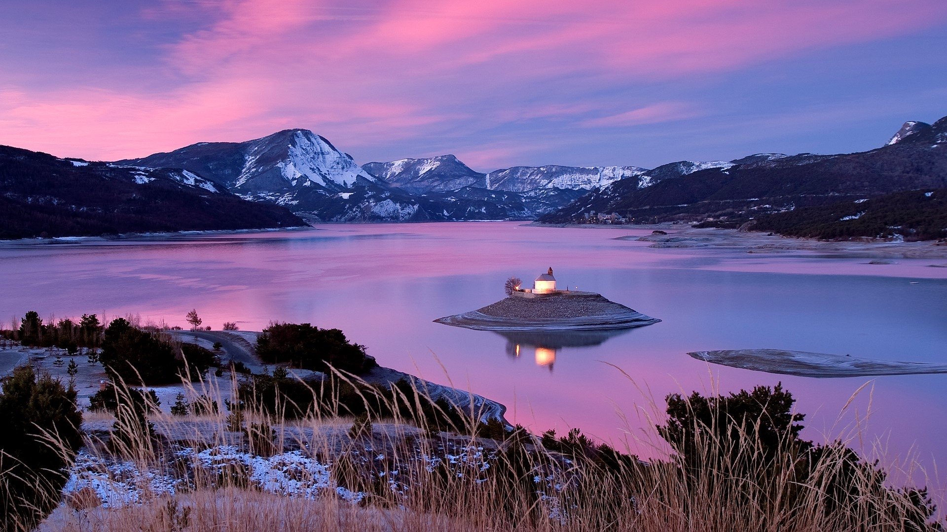 HD PC desktop wallpaper/background: a religious chapel on a small island in a mountain lake at sunset, pink sky and snow-capped peaks reflected in calm, tranquil water.