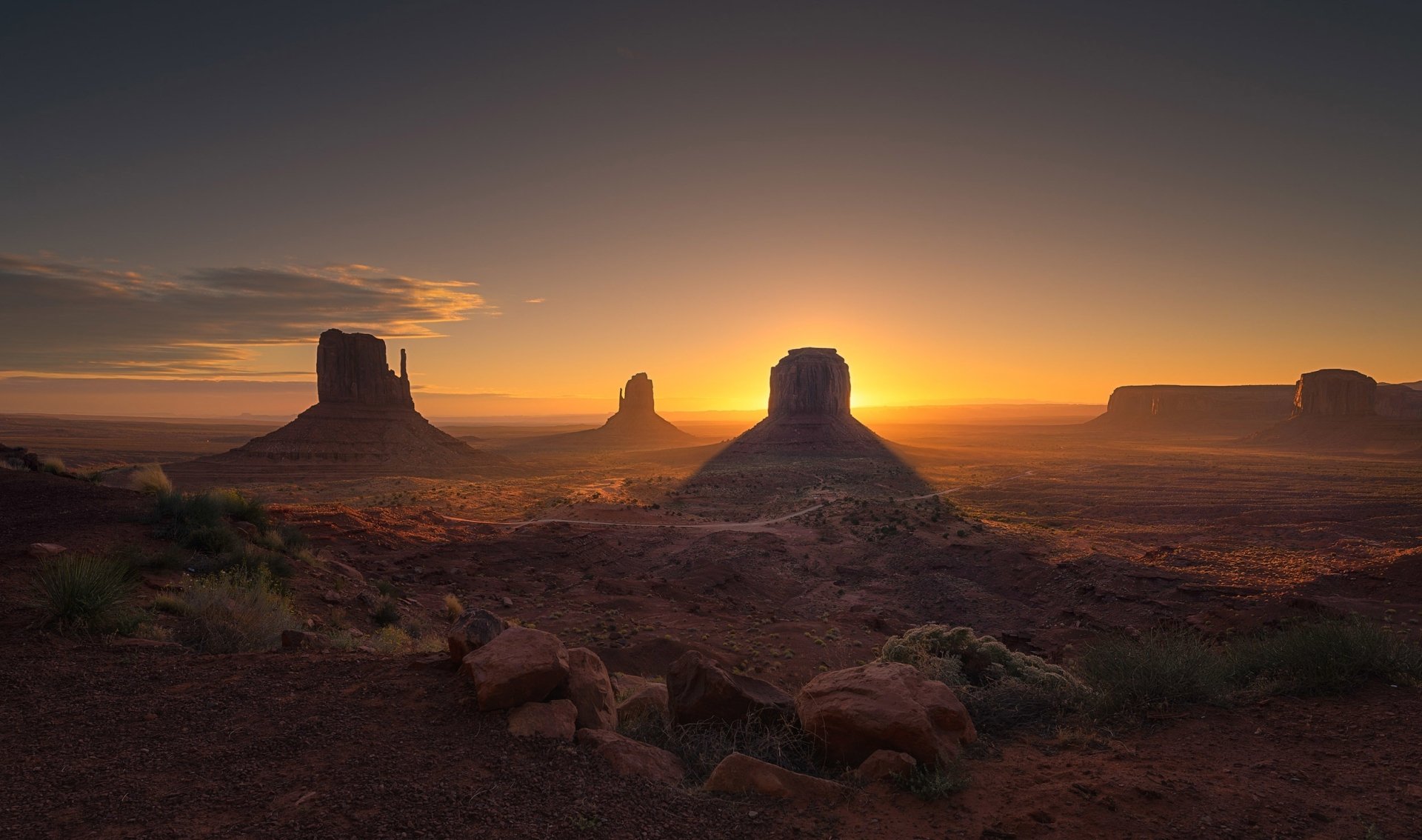 HD desktop wallpaper of Monument Valley at sunset, showcasing iconic rock formations bathed in warm, natural light against a serene sky.