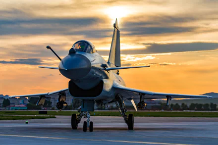 HD desktop wallpaper of a Chengdu J-10 military jet fighter warplane on the runway at sunset, showcasing the sleek aircraft against a dramatic sky.
