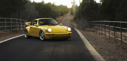 Yellow Porsche 911 Carrera RS sports car parked on a winding road, captured in HD for a desktop wallpaper background.