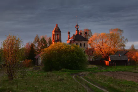 HD desktop wallpaper of a church silhouetted against a dramatic sunset sky, surrounded by trees with glowing autumn foliage.