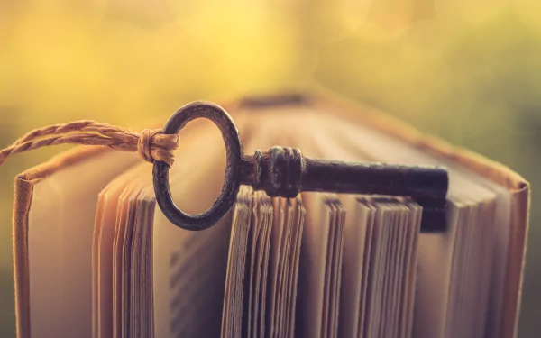 4K Ultra HD PC desktop wallpaper: macro shot of an antique key resting on the open pages of a book, warm bokeh background highlighting the man-made object in soft focus.