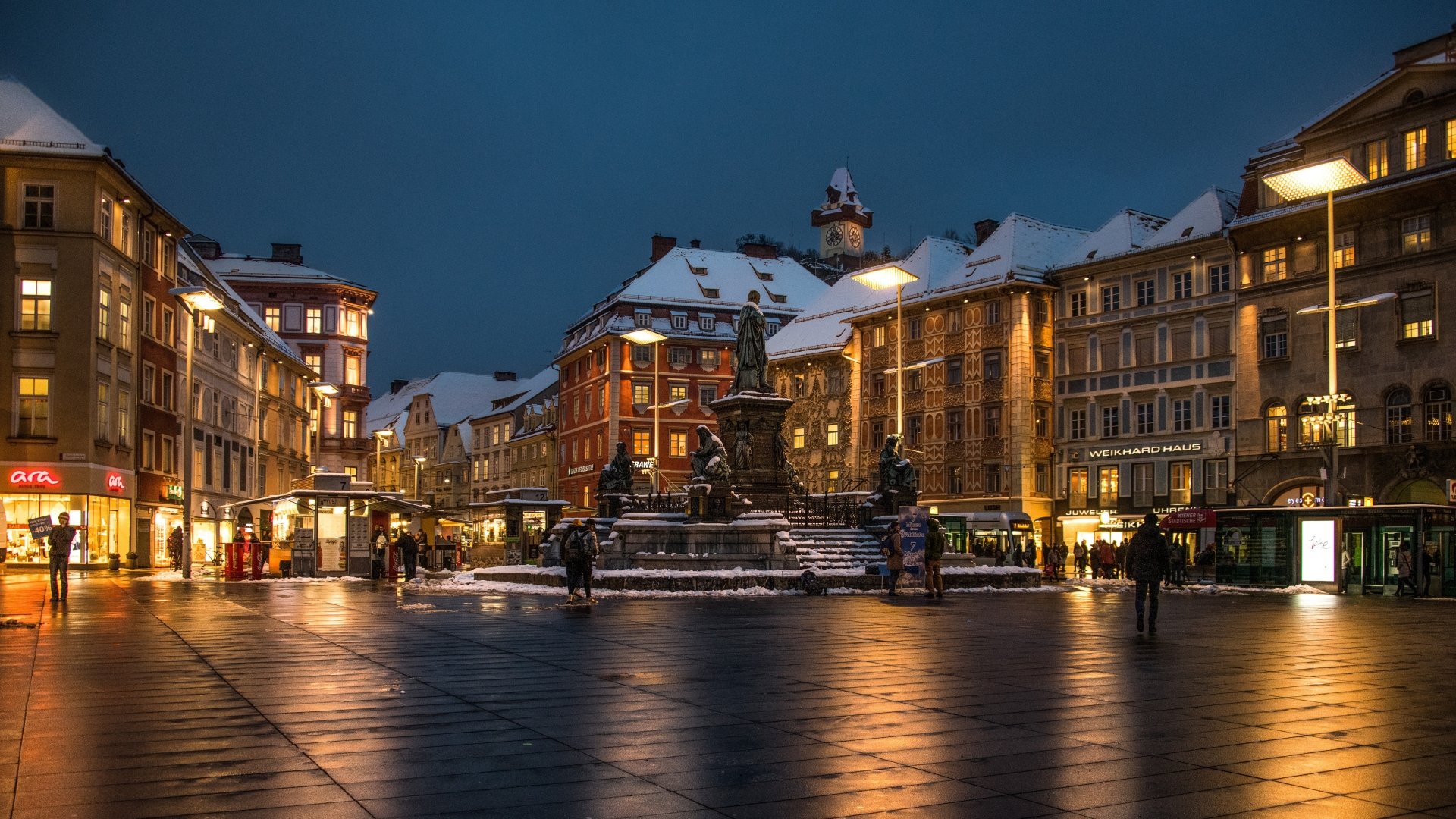 Evening view of Graz town square, Austria, showcasing historic buildings and a central fountain under a deep blue sky in 4K Ultra HD.