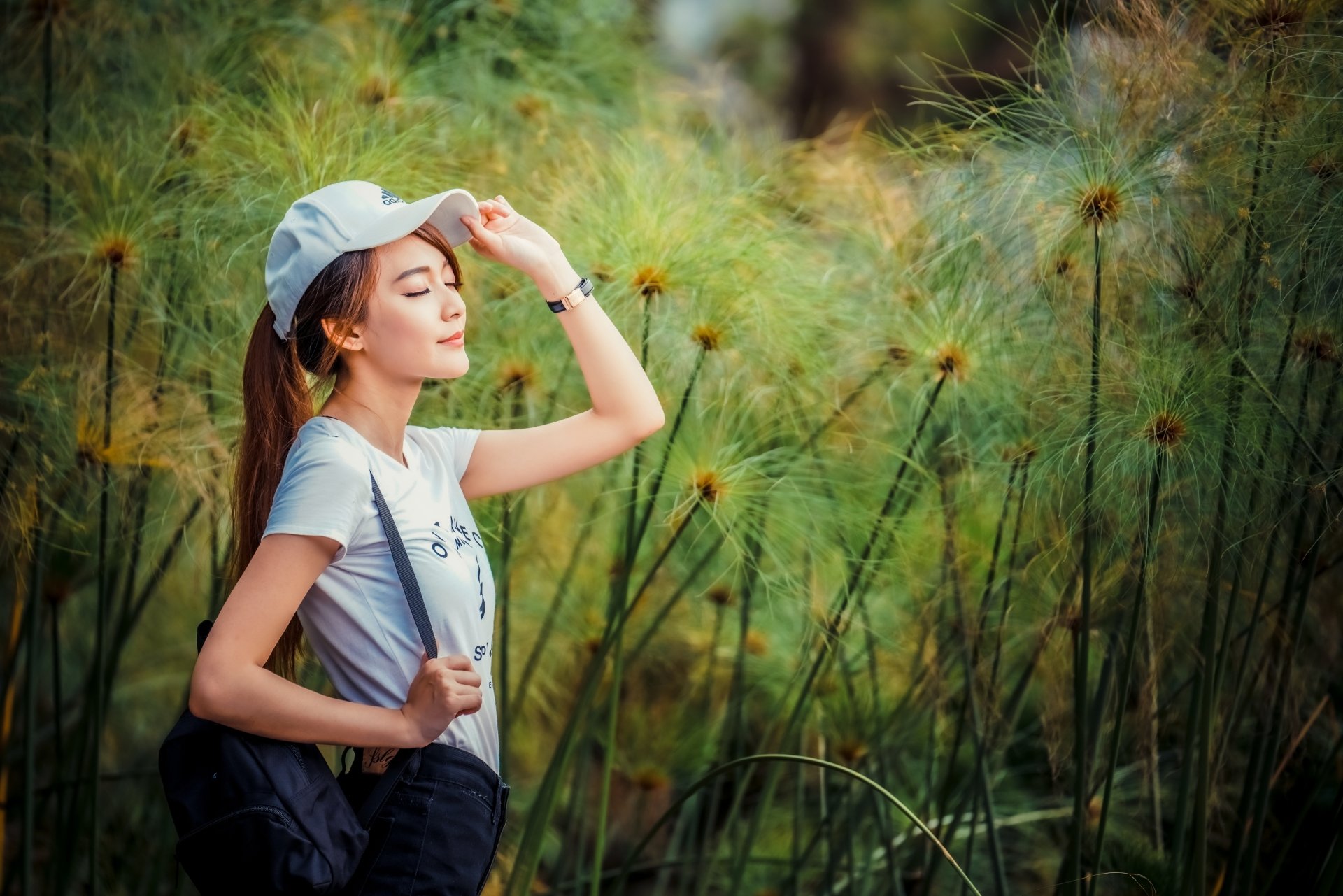 4K Ultra HD desktop wallpaper: portrait of a woman in a cap with a serene mood and model-like pose among tall green reeds.