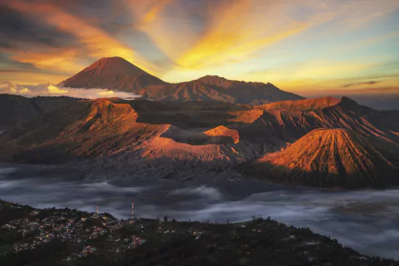 Mount Bromo volcano and surrounding peaks in Indonesia at sunset, golden light on ridges and caldera with mist-filled valley — 5K Ultra HD desktop wallpaper.