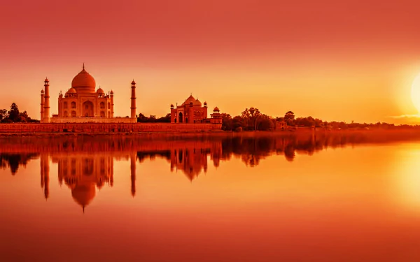 HD desktop wallpaper of the Taj Mahal in Agra, India, a man-made domed monument reflected in calm water at sunset.