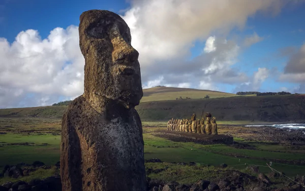 HD wallpaper of Rapa Nui's iconic man-made Moai statues on Easter Island, part of Chile's protectorate, set against a dramatic sky and rolling hills.