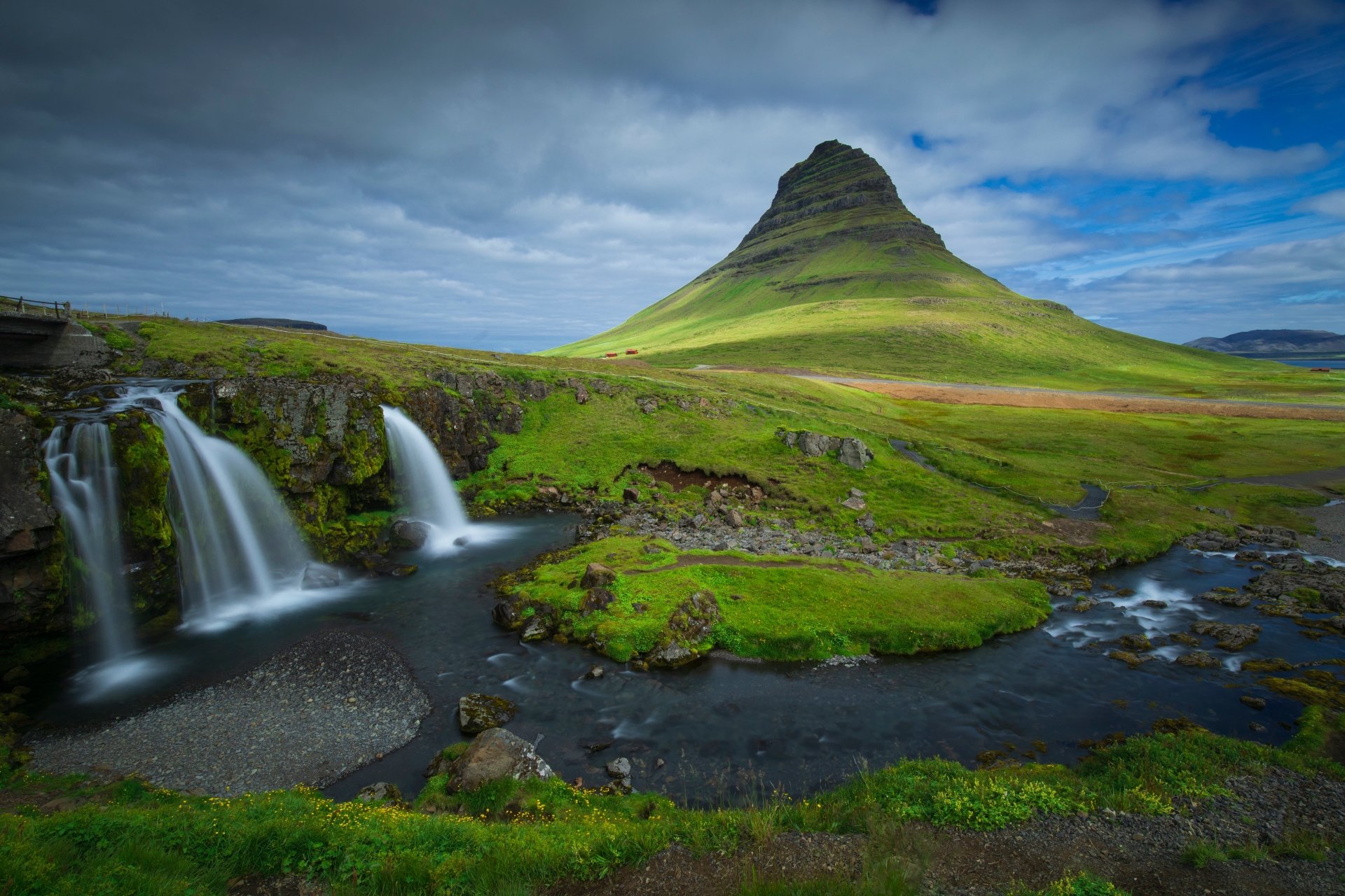 Kirkjufoss waterfall with Kirkjufell mountain rising behind in Iceland, lush green slopes and a winding river — 5K Ultra HD PC desktop wallpaper.