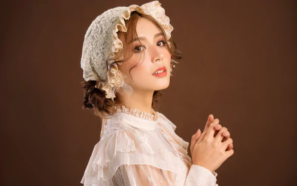 4K Ultra HD desktop wallpaper featuring an Asian woman model wearing a lace bonnet and delicate white dress with soft pink lipstick against a brown background.