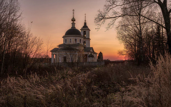 4K Ultra HD desktop wallpaper featuring a serene church at sunset, surrounded by bare trees and tall grass in a peaceful natural setting.