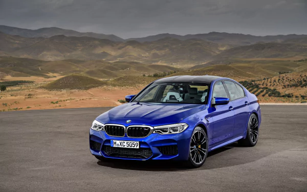 Blue BMW M5 sports sedan parked on open road with rolling hills; high-resolution 4K Ultra HD PC desktop wallpaper showcasing a sleek performance vehicle.