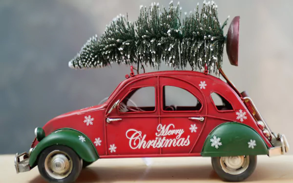 4K Ultra HD PC wallpaper of a decorative red toy Christmas car reading Merry Christmas, carrying a snowy Christmas tree on its roof, holiday snowflake accents.