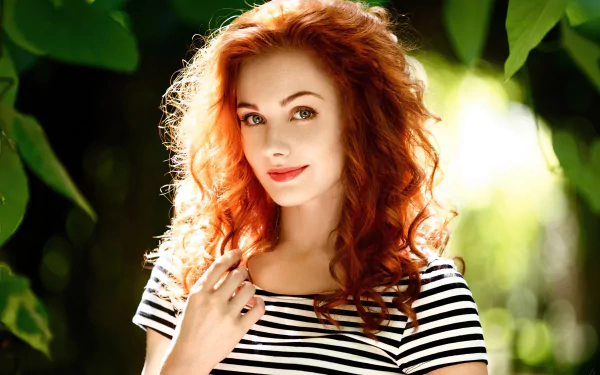4K Ultra HD desktop wallpaper of a redhead woman model with curled hair, wearing striped clothes and red lipstick, posing outdoors against a lush green background.