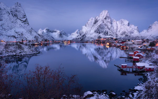 Snow-covered mountains and a village reflect clearly in a calm fjord at the Lofoten Islands, Norway, captured in stunning 4K Ultra HD.
