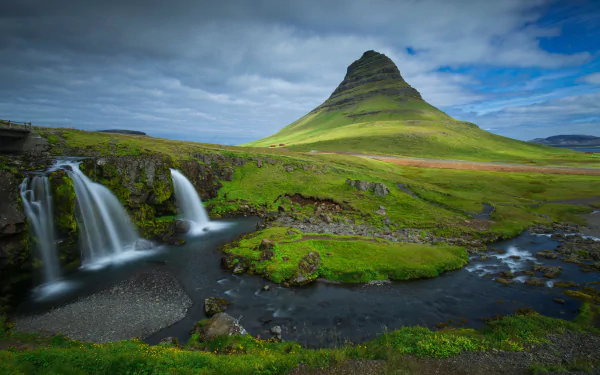 Kirkjufoss waterfall with Kirkjufell mountain rising behind in Iceland, lush green slopes and a winding river — 5K Ultra HD PC desktop wallpaper.