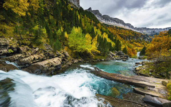 5K Ultra HD PC desktop wallpaper and background of a Spanish national park: waterfall cascading into turquoise pools through an autumn mountain forest, a vivid nature landscape.
