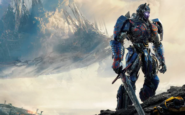 HD desktop wallpaper features Optimus Prime from Transformers: The Last Knight, standing heroically amidst a dramatic, cloudy landscape with sharp mountains in the background.
