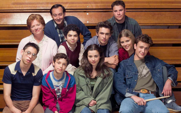 HD wallpaper featuring the cast of Freaks and Geeks posing together on gymnasium bleachers.