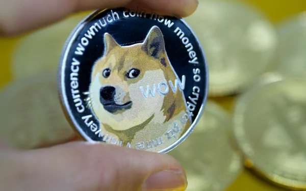 HD desktop wallpaper of a hand holding a Dogecoin with the Shiba Inu mascot, against a backdrop of gold coins.