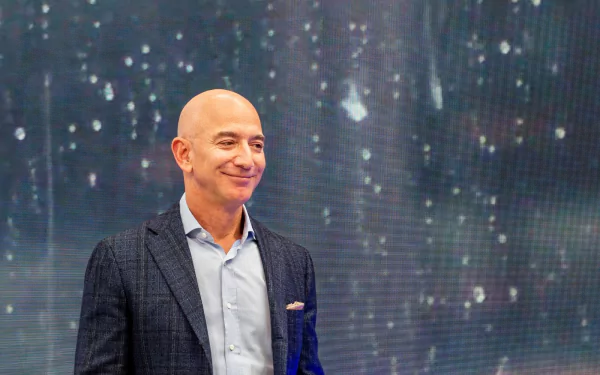 Jeff Bezos smiles while standing against a sparkling background, creating an engaging and dynamic HD desktop wallpaper for fans and followers of the celebrity.
